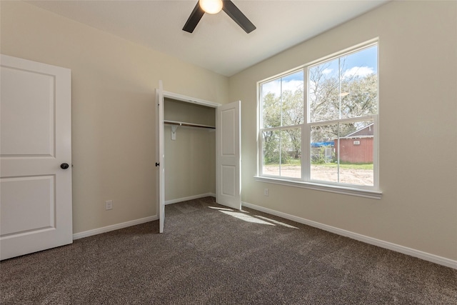 unfurnished bedroom featuring a closet, a ceiling fan, baseboards, and dark colored carpet