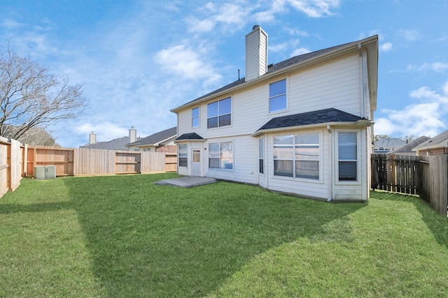 rear view of house featuring a lawn, a fenced backyard, and a chimney