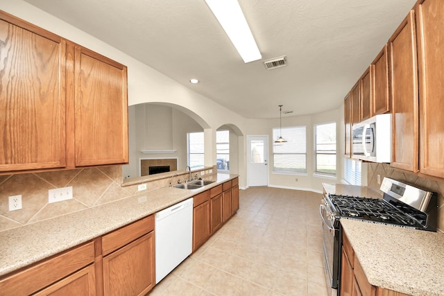 kitchen with tasteful backsplash, visible vents, arched walkways, white appliances, and a sink