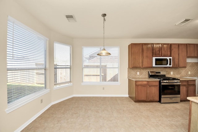 kitchen with white microwave, stainless steel range with gas cooktop, visible vents, and light countertops