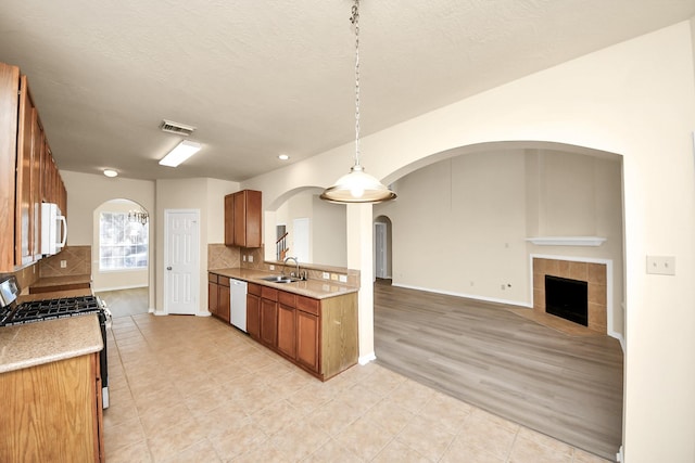 kitchen featuring arched walkways, visible vents, white appliances, and a sink