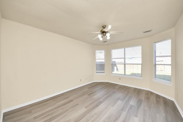 spare room featuring baseboards, wood finished floors, visible vents, and ceiling fan