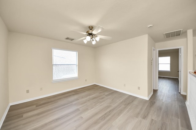 empty room with visible vents, baseboards, light wood-style floors, and a ceiling fan