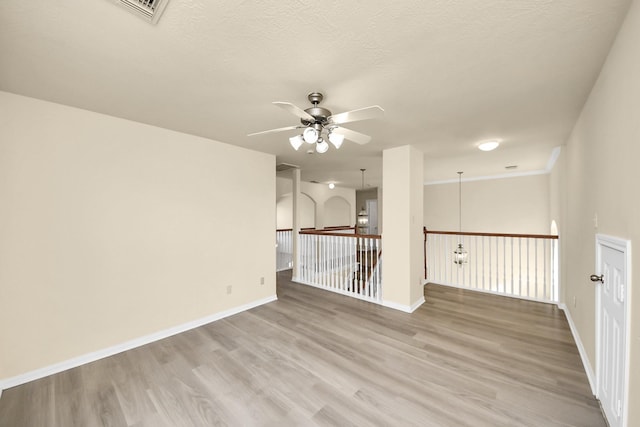 empty room featuring baseboards, a textured ceiling, light wood-style flooring, and a ceiling fan