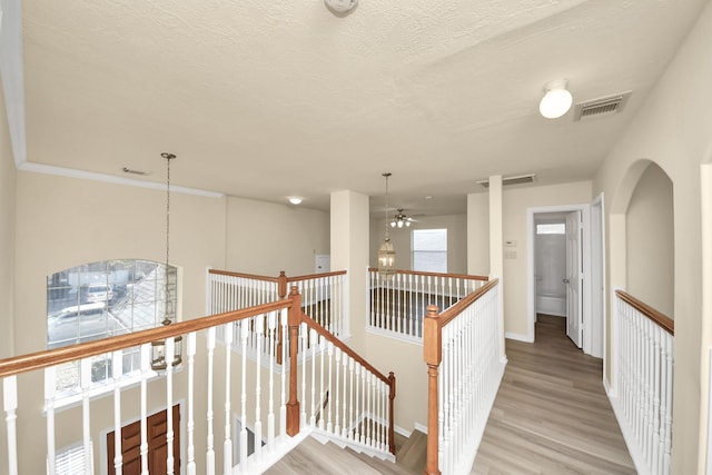 hall featuring an upstairs landing, visible vents, and light wood-type flooring