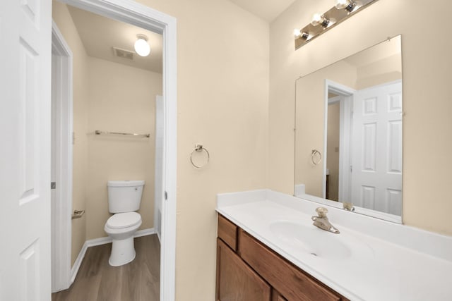 bathroom with visible vents, baseboards, toilet, wood finished floors, and vanity