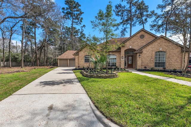 view of front facade with a front yard, brick siding, and a detached garage