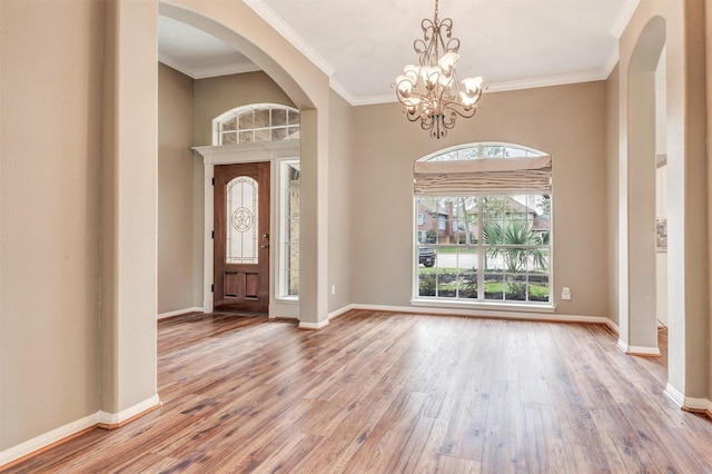 entryway featuring arched walkways, baseboards, and wood finished floors