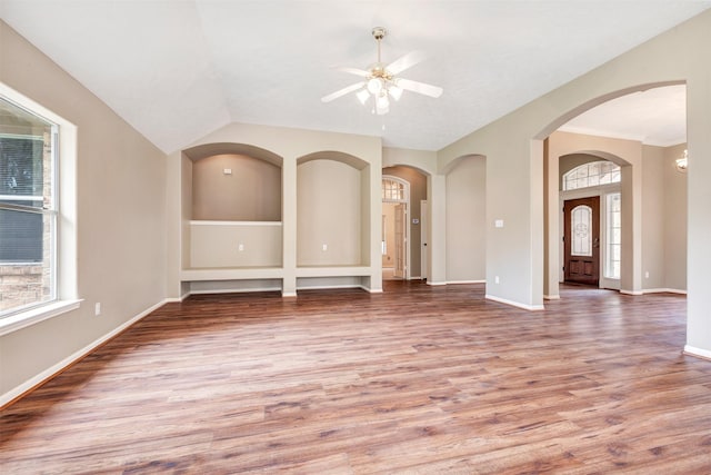 unfurnished room with vaulted ceiling, light wood-style floors, baseboards, and ceiling fan