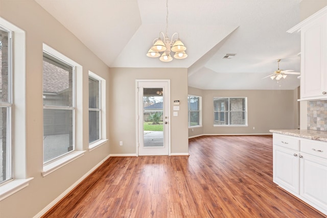 interior space featuring tasteful backsplash, visible vents, vaulted ceiling, an inviting chandelier, and white cabinets