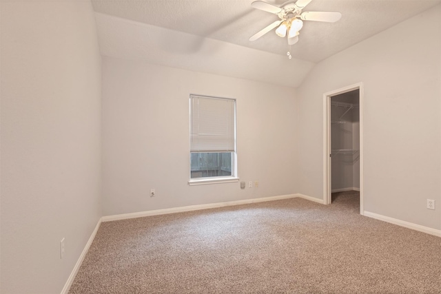 empty room with ceiling fan, lofted ceiling, baseboards, and light carpet