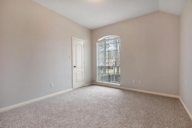 empty room featuring baseboards, carpet, and lofted ceiling