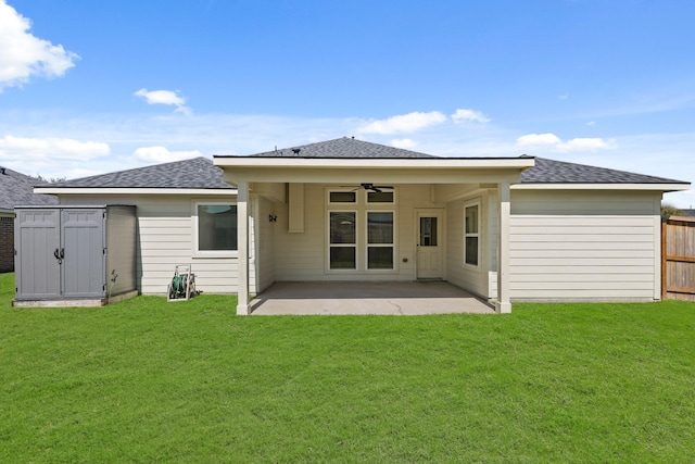 rear view of house with fence, ceiling fan, a storage shed, a patio area, and a lawn