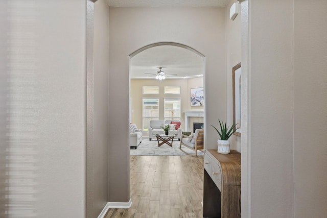 hallway featuring arched walkways and light wood-type flooring