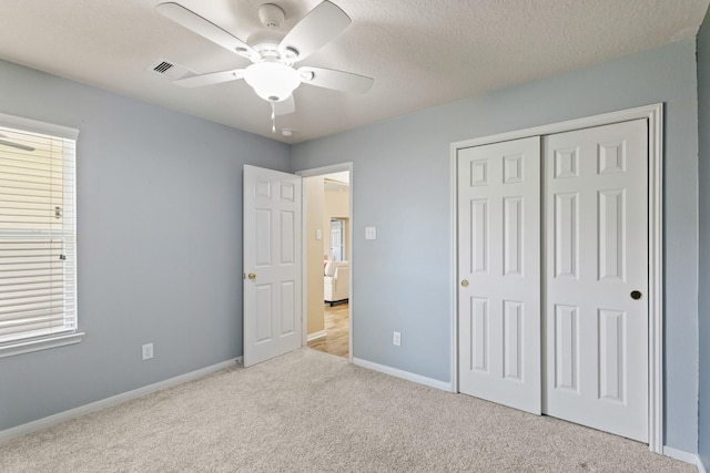 unfurnished bedroom with baseboards, visible vents, carpet floors, a closet, and a textured ceiling