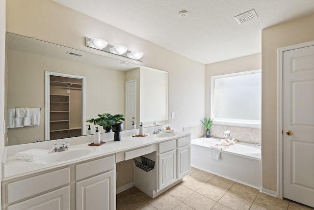 bathroom featuring visible vents, double vanity, a sink, tile patterned floors, and a bath