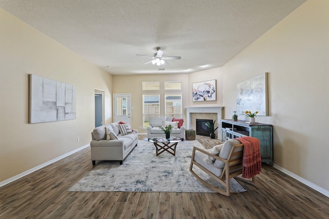 living room with baseboards, a textured ceiling, ceiling fan, and dark wood finished floors