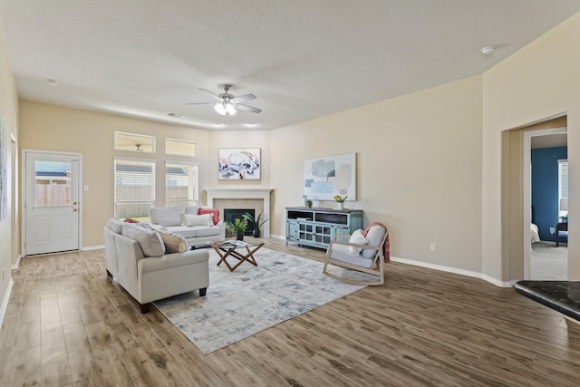 living room with visible vents, baseboards, ceiling fan, wood finished floors, and a textured ceiling