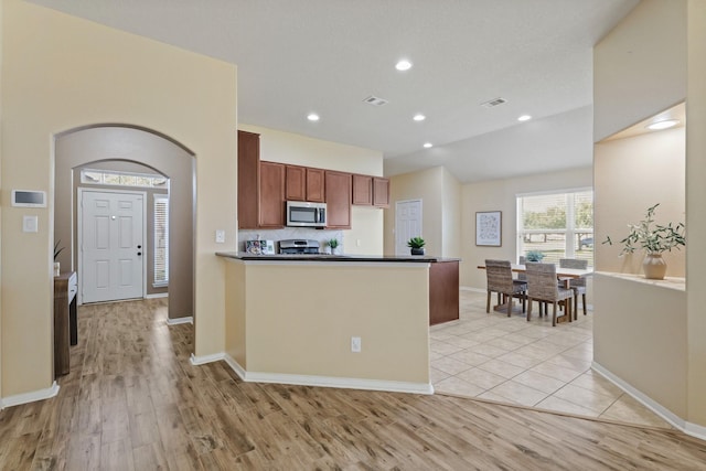 kitchen featuring visible vents, dark countertops, appliances with stainless steel finishes, and a peninsula