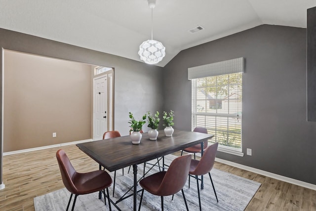 dining space featuring vaulted ceiling, baseboards, visible vents, and light wood finished floors