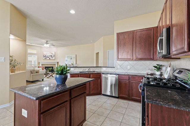 kitchen featuring backsplash, appliances with stainless steel finishes, a peninsula, light tile patterned flooring, and a ceiling fan