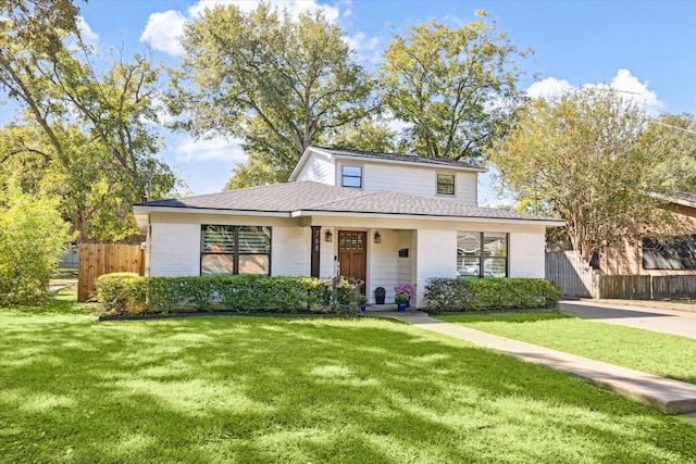 view of front of property featuring brick siding, a shingled roof, a front lawn, and fence