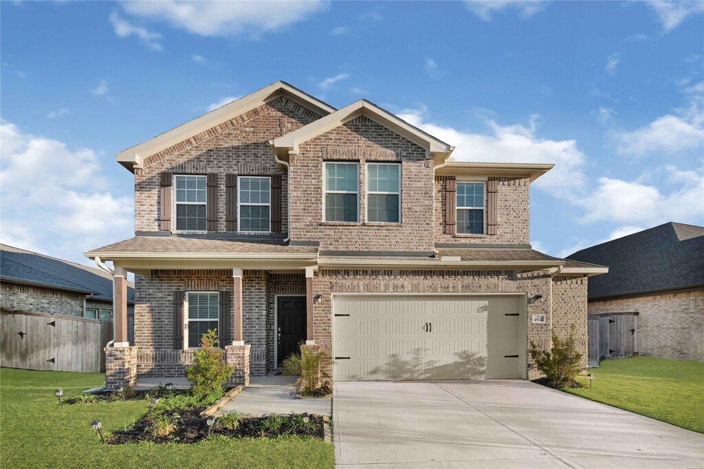 4922 Magnolia Springs Dr, Pearland, TX 77584 - craftsman-style home with a front yard, an attached garage, covered porch, concrete driveway, and brick siding