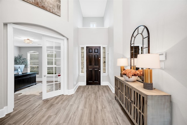 entrance foyer featuring baseboards, a high ceiling, and wood finished floors