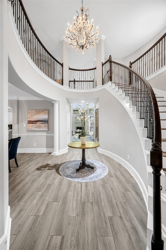 entrance foyer featuring wood finished floors, stairway, a high ceiling, baseboards, and a chandelier