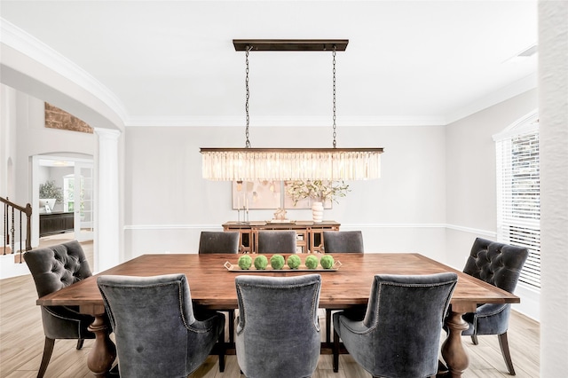 dining room with arched walkways, wood finished floors, ornamental molding, and ornate columns