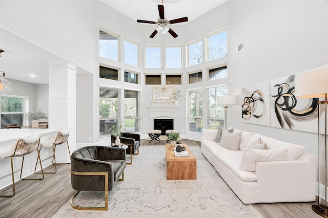 living room with visible vents, plenty of natural light, wood finished floors, a fireplace, and ceiling fan