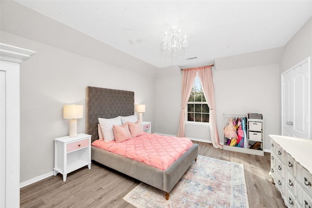 bedroom featuring visible vents, baseboards, an inviting chandelier, and light wood finished floors