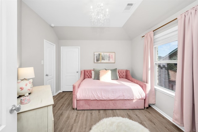 bedroom with visible vents, wood finished floors, baseboards, and vaulted ceiling