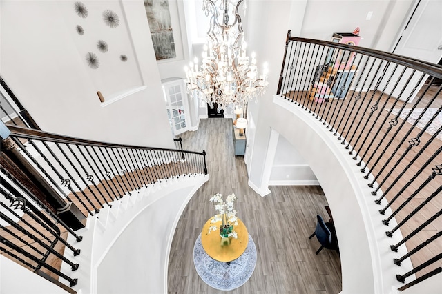 stairs featuring baseboards, a notable chandelier, and wood finished floors