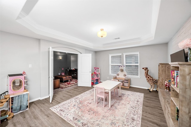 game room with a tray ceiling, baseboards, visible vents, and wood finished floors