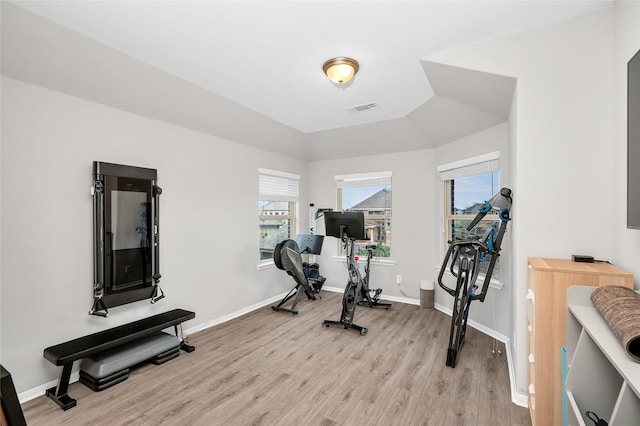 workout area featuring visible vents, light wood-style flooring, and baseboards