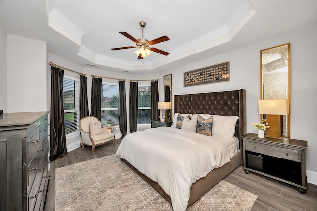 bedroom featuring a tray ceiling, wood finished floors, and ornamental molding