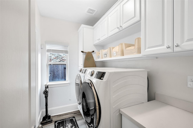 laundry room with wood finished floors, baseboards, visible vents, washing machine and clothes dryer, and cabinet space