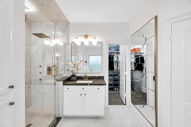 full bathroom with a spacious closet, a shower stall, vanity, and marble finish floor