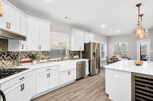 kitchen with light wood-style flooring, beverage cooler, white cabinetry, stainless steel appliances, and light countertops