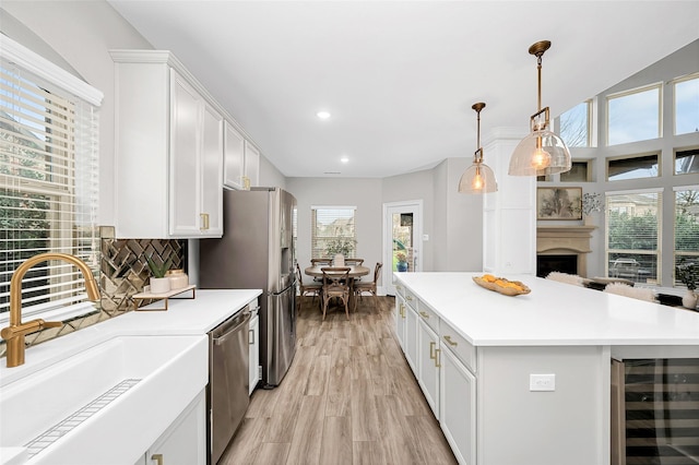 kitchen with a sink, stainless steel appliances, light countertops, wine cooler, and white cabinets