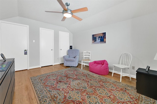 living area with vaulted ceiling, wood finished floors, baseboards, and ceiling fan