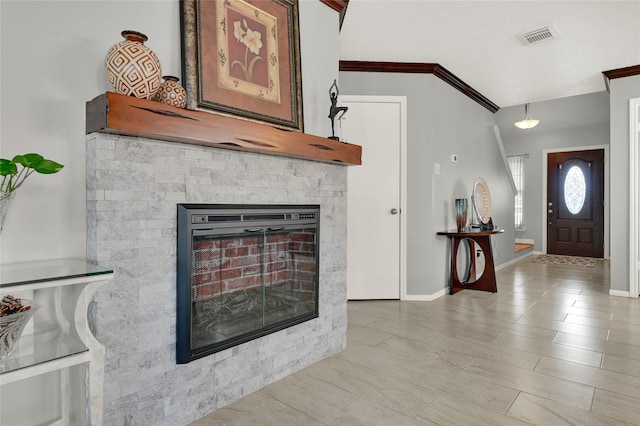 entrance foyer with visible vents, a fireplace, baseboards, and ornamental molding