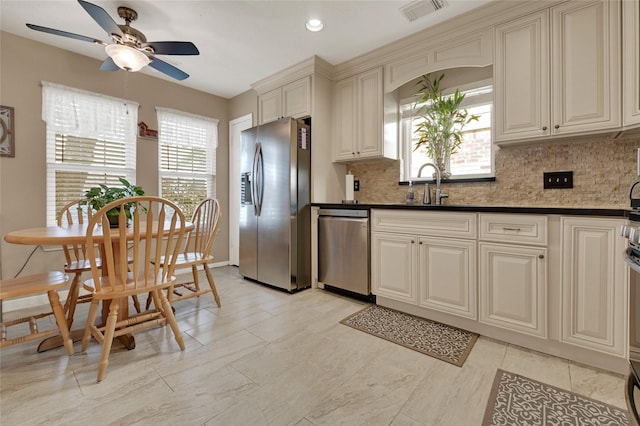 kitchen with visible vents, a sink, appliances with stainless steel finishes, decorative backsplash, and ceiling fan