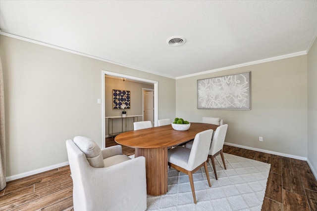 dining area with visible vents, crown molding, baseboards, and wood finished floors