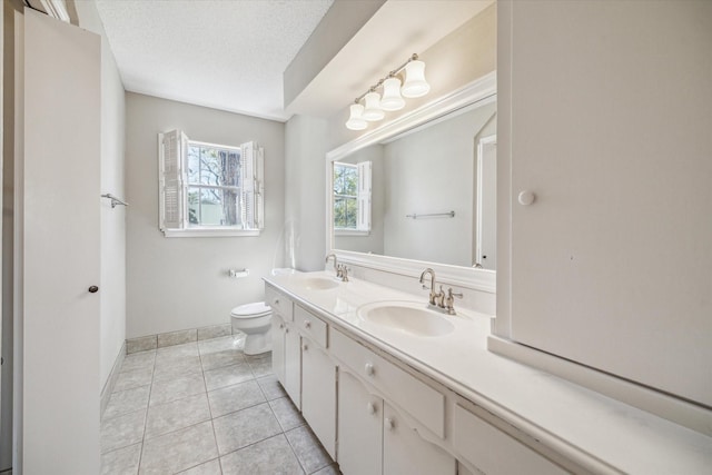 bathroom with a sink, toilet, tile patterned floors, and a textured ceiling