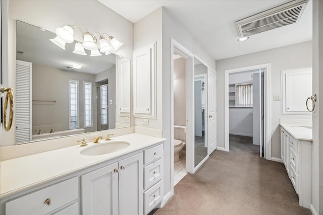 full bathroom with visible vents, toilet, two vanities, a notable chandelier, and a sink