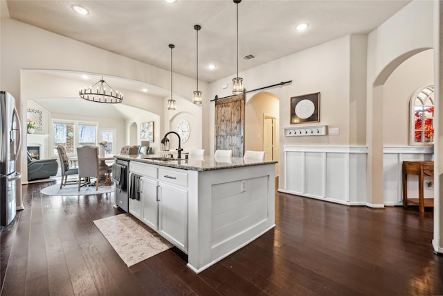 kitchen with visible vents, a sink, open floor plan, stainless steel appliances, and light stone countertops