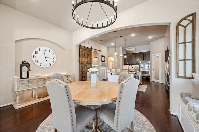 dining room featuring dark wood finished floors, recessed lighting, arched walkways, a barn door, and a notable chandelier