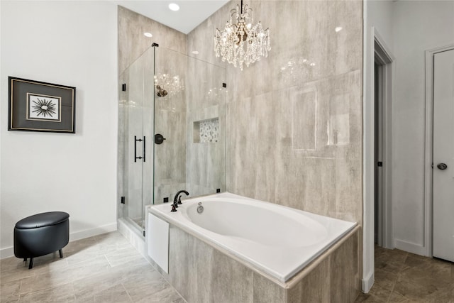 bathroom featuring a garden tub, a notable chandelier, baseboards, and a stall shower